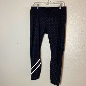 Athleta black leggings with gray design and white right leg strip. Size Large.